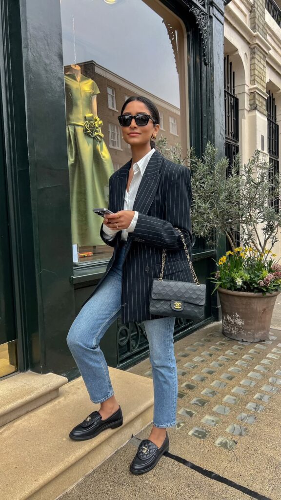 Classy fall outfit with navy pinstripe blazer, white shirt, blue jeans, and black loafers
