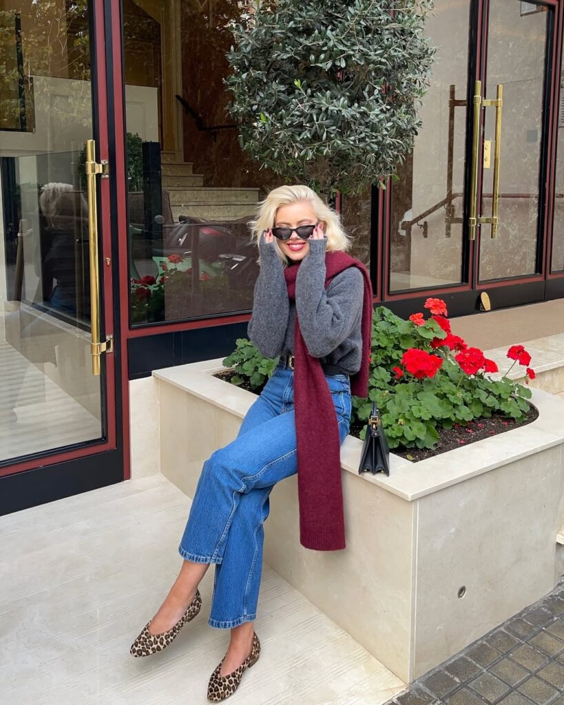 Fall outfit with grey sweater, burgundy scarf, blue jeans, and leopard print flats
