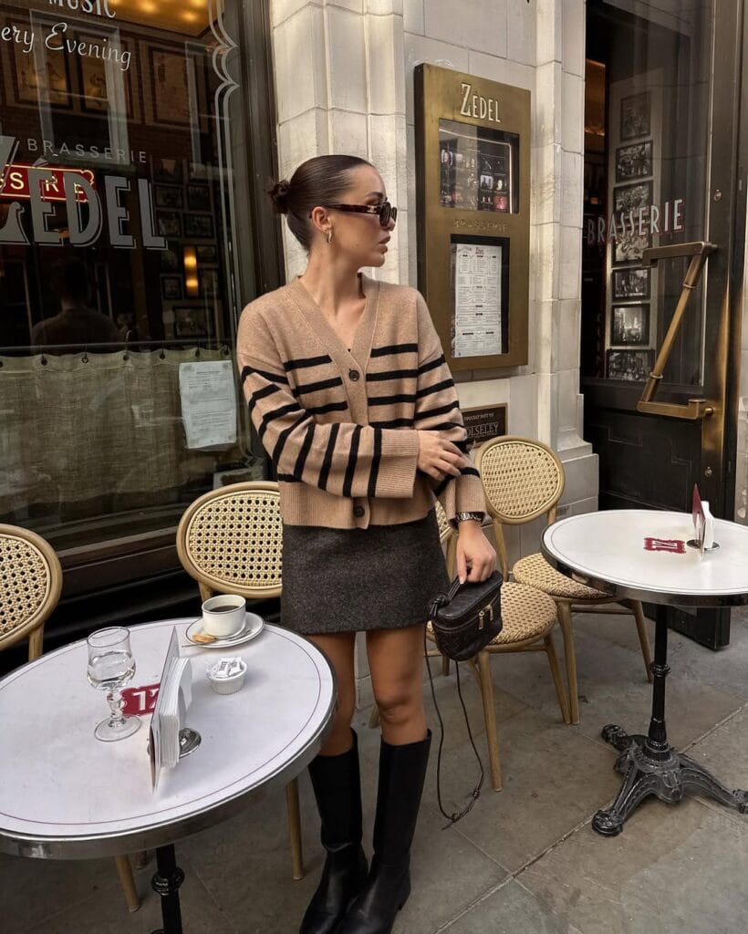Chic fall outfit with striped tan cardigan, grey mini skirt, and black knee-high boots