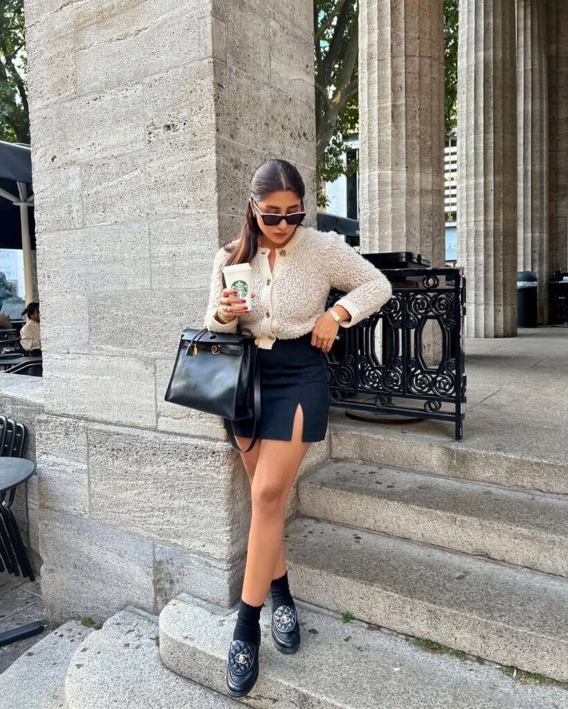 Fall outfit with cream textured cardigan, black mini skirt, and classic loafers