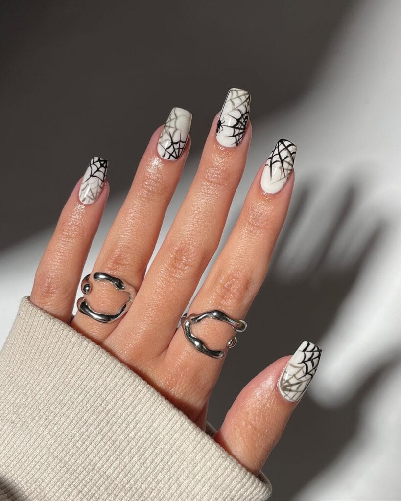 White coffin nails with bold black spiderweb nail art, matte and glossy finish for Halloween.