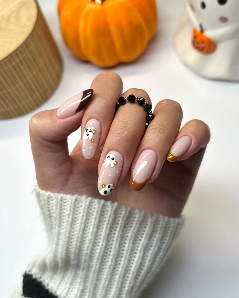 Almond nails with caramel French tips, cute ghost nail art, and polka dot accents for Halloween.