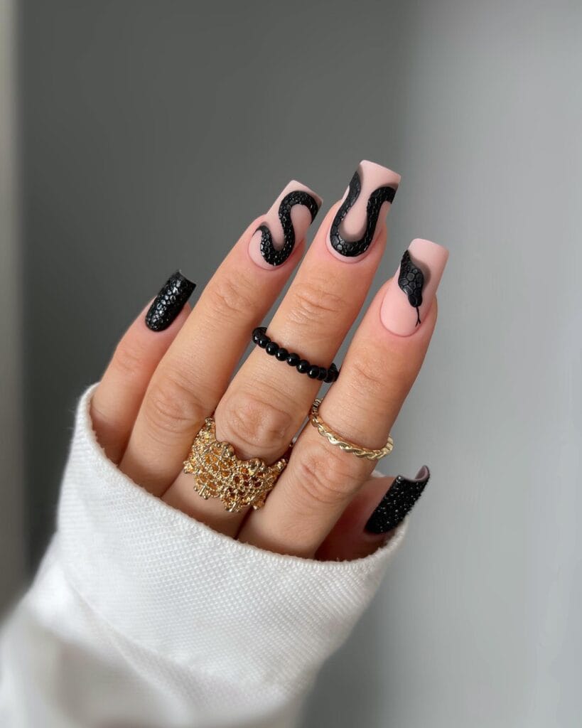  Nude square nails with textured black snake nail art and black glitter accents for Halloween.