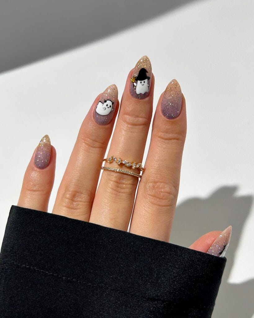  Sparkly ombré Halloween nails with ghost and witch designs on almond-shaped nails.