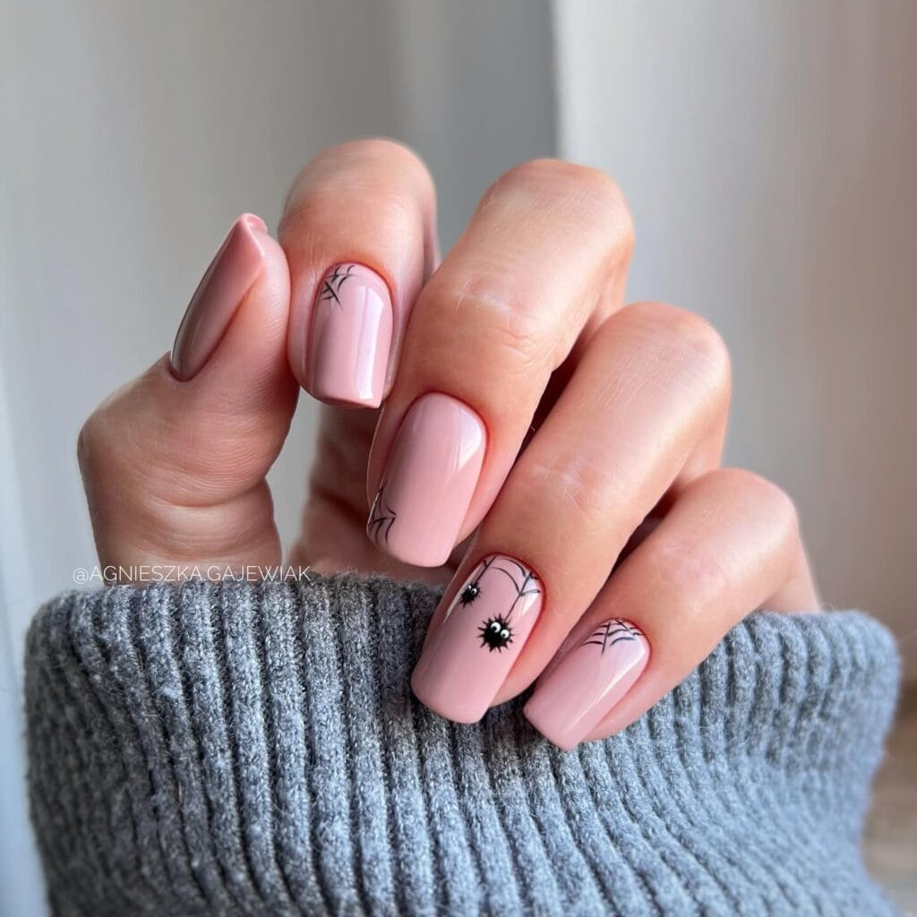  Soft pink square nails with fine black spiderwebs and spider art for Halloween.