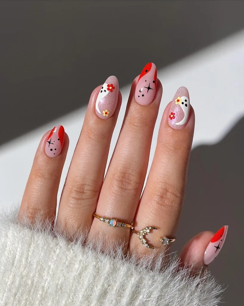 Pink Halloween nails with red moons, ghosts, florals, and stars on almond-shaped nails.
