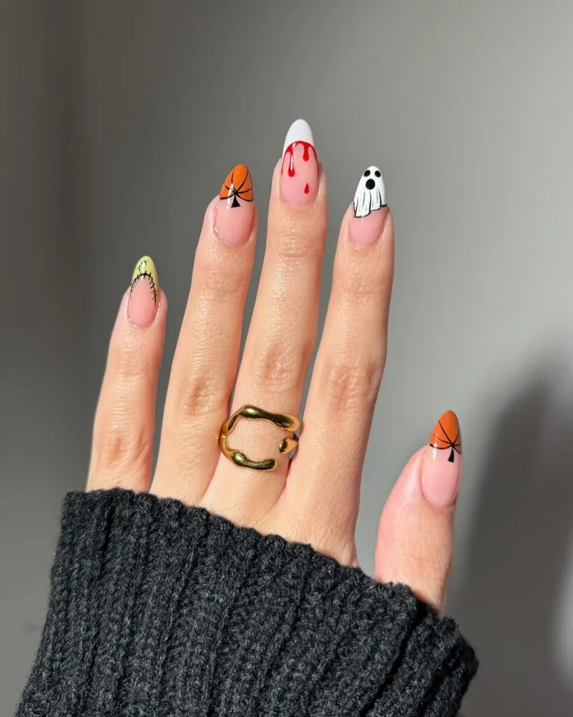 Halloween nails with stitched monster, spider, blood drip, and ghost designs on almond shape.
