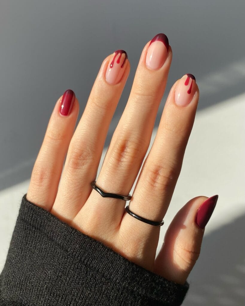 Burgundy French tip Halloween nails with blood drip accent on almond-shaped nails.
