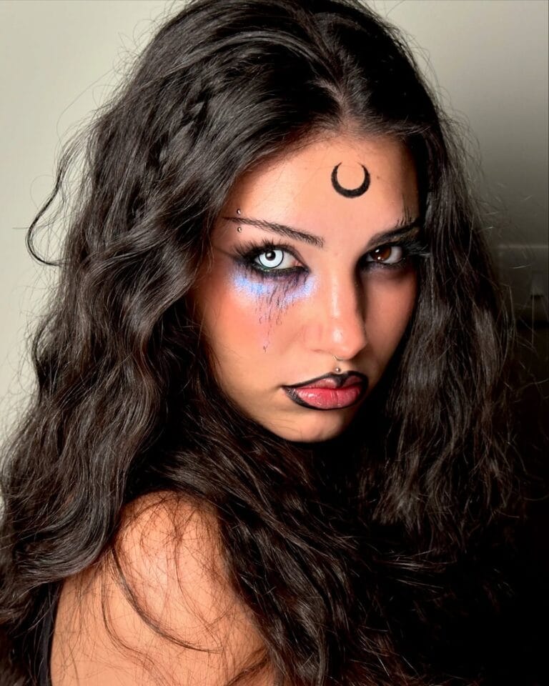 Halloween makeup with crescent moon, blue shadow, and black lipstick for a witchy, cosmic vibe.