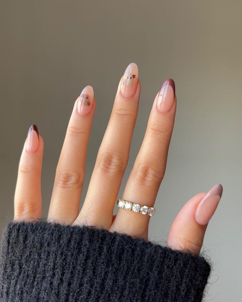 Mauve almond nails with tiny florals and white ghost accents for a soft Halloween look.