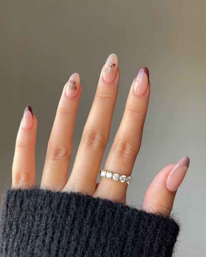 Mauve almond nails with tiny florals and white ghost accents for a soft Halloween look.