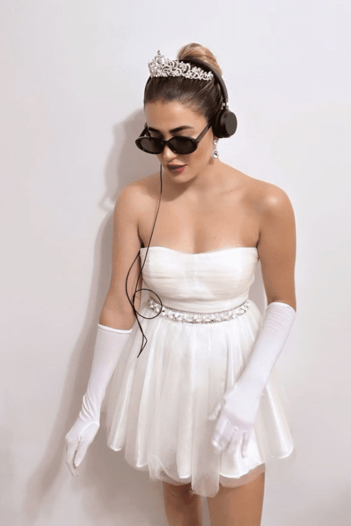Halloween costume with white tulle dress, tiara, headphones, and gloves—Princess Diaries’ Mia Thermopolis for a chic Halloween look.