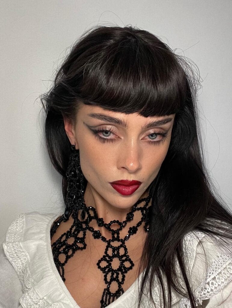 Gothic Halloween makeup with bold winged eyeliner and deep red lips.