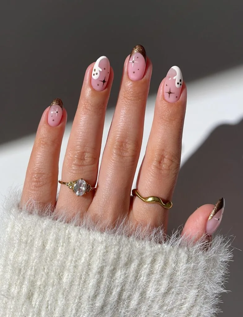 Bronze French tip Halloween nails with ghosts and star accents on almond shape.
