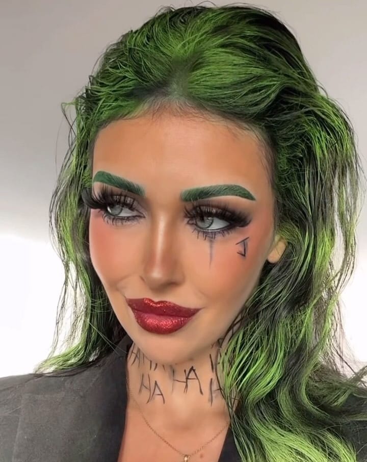 Joker-inspired Halloween makeup with green hair, emerald brows, and red lips.