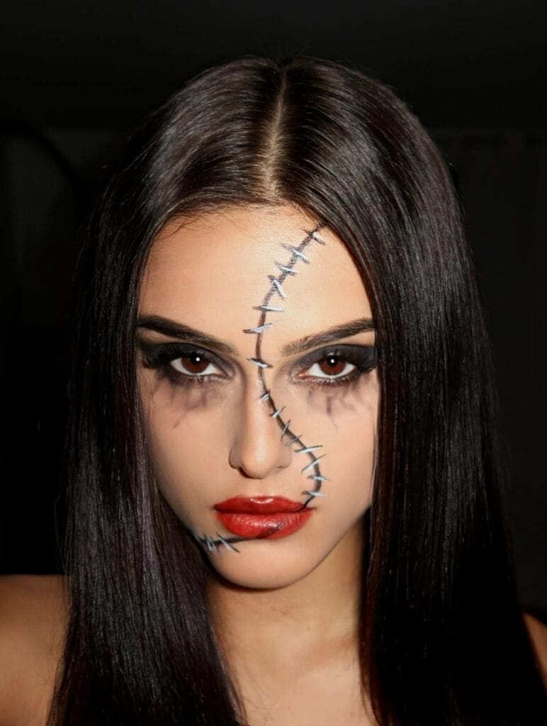 Halloween makeup with black stitches across the face and bold red lips for a gothic doll effect.