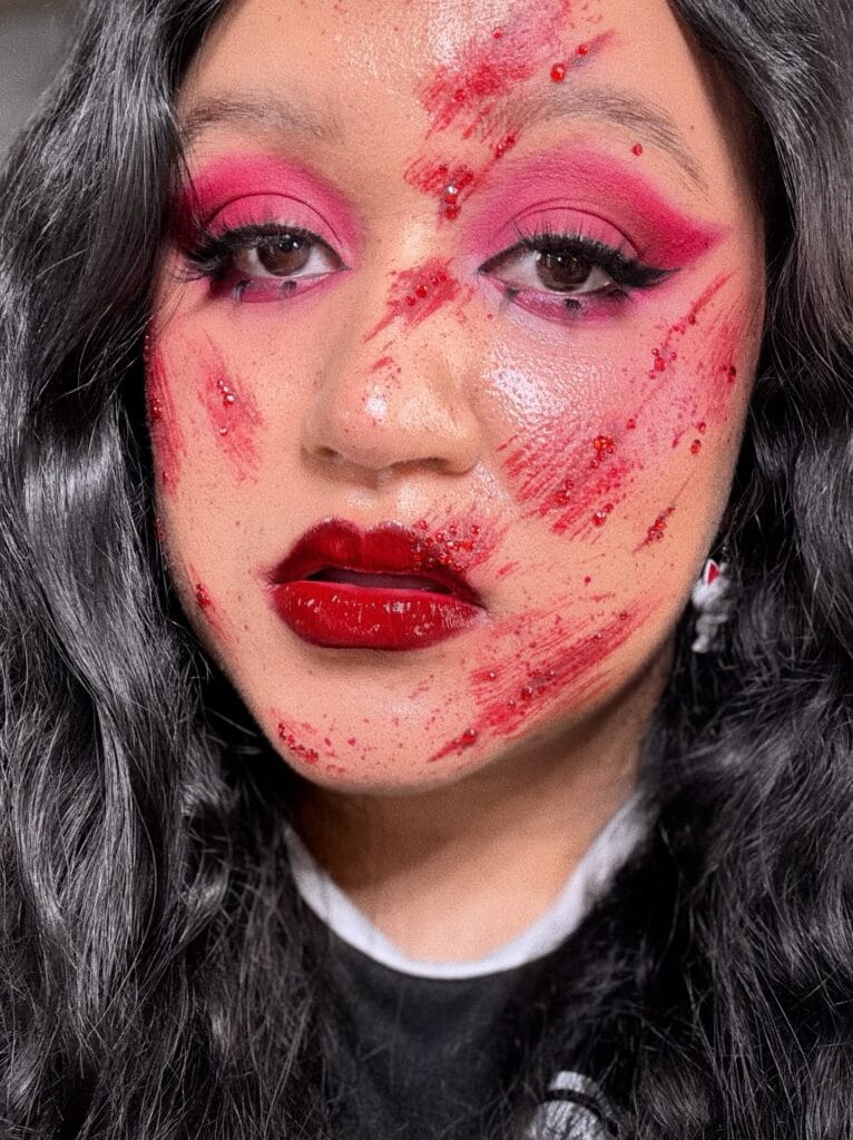 Bloody doll Halloween makeup with pink eyeshadow and red blood smears.