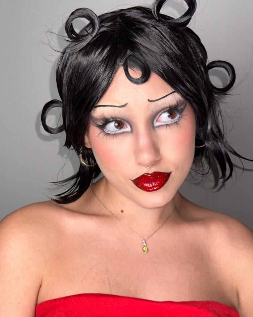 Cartoon pin-up Halloween makeup with exaggerated brows and glossy red lips.