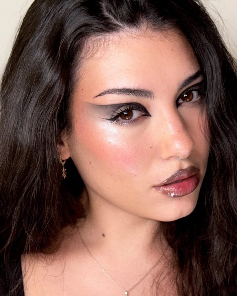 Cat eye Halloween makeup with dramatic winged eyeliner and glossy brown lips.