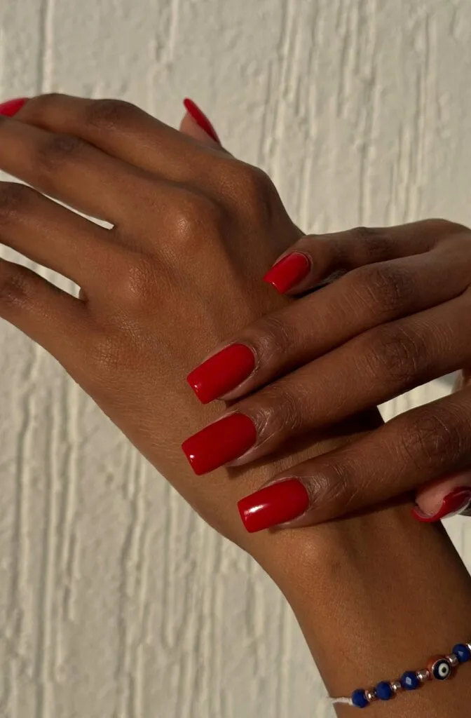 Classic square red old money nails, glossy and bold, styled with blue evil eye bracelet.