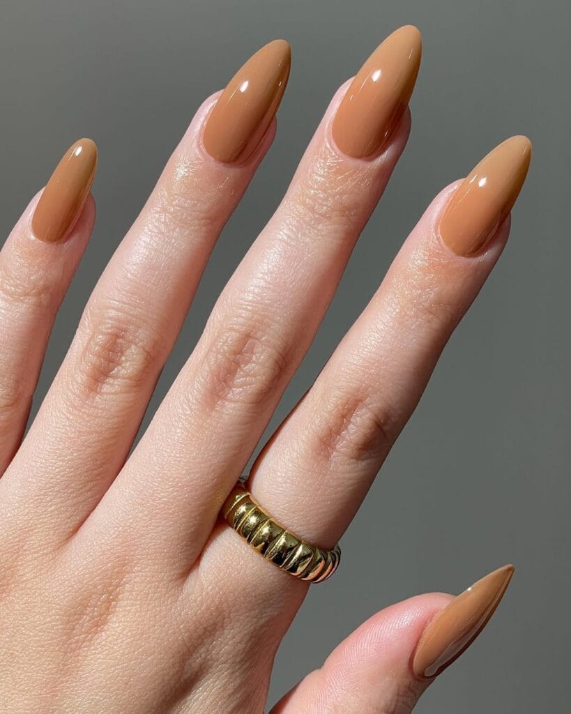 Almond neutral nails, rich caramel brown, glossy and warm fall-inspired manicure.

