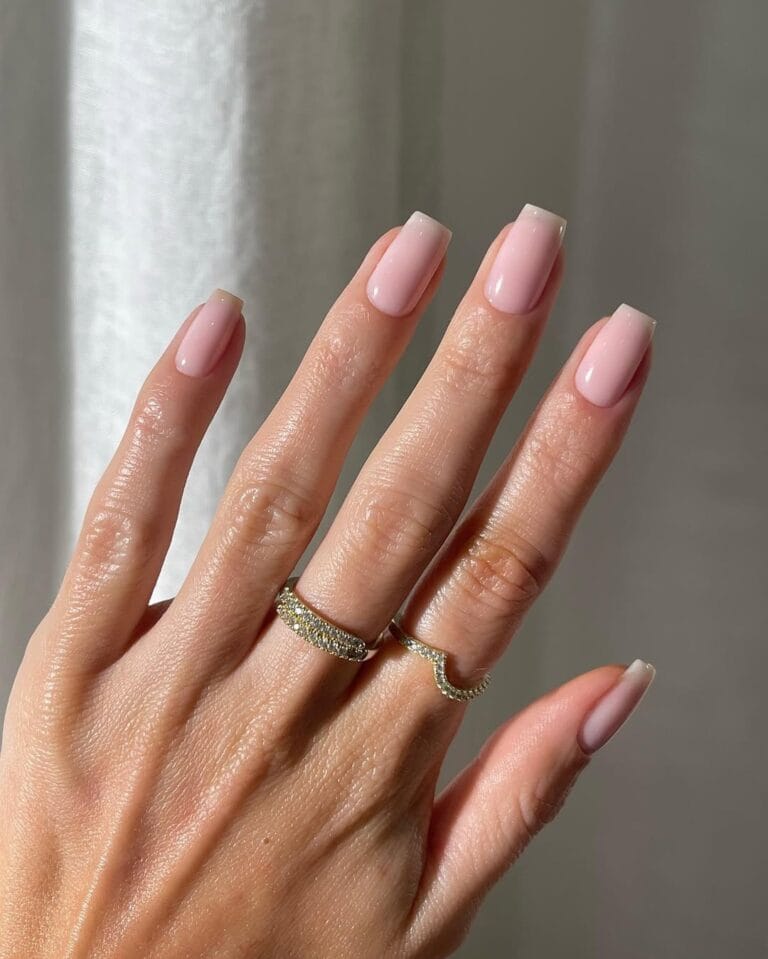 Blush pink neutral nails, medium square shape, glossy finish, styled with gold rings.
