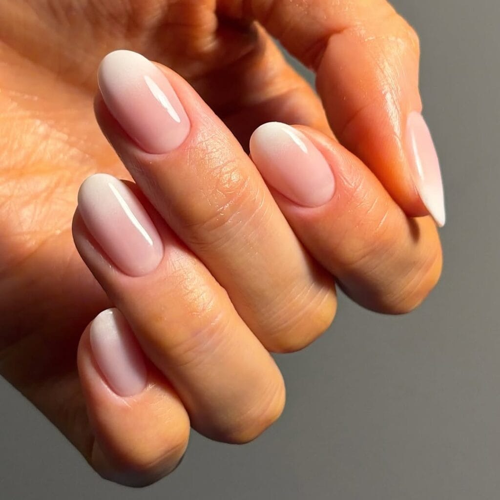Baby pink neutral almond nails with milky white ombré, glossy, delicate, and feminine.
