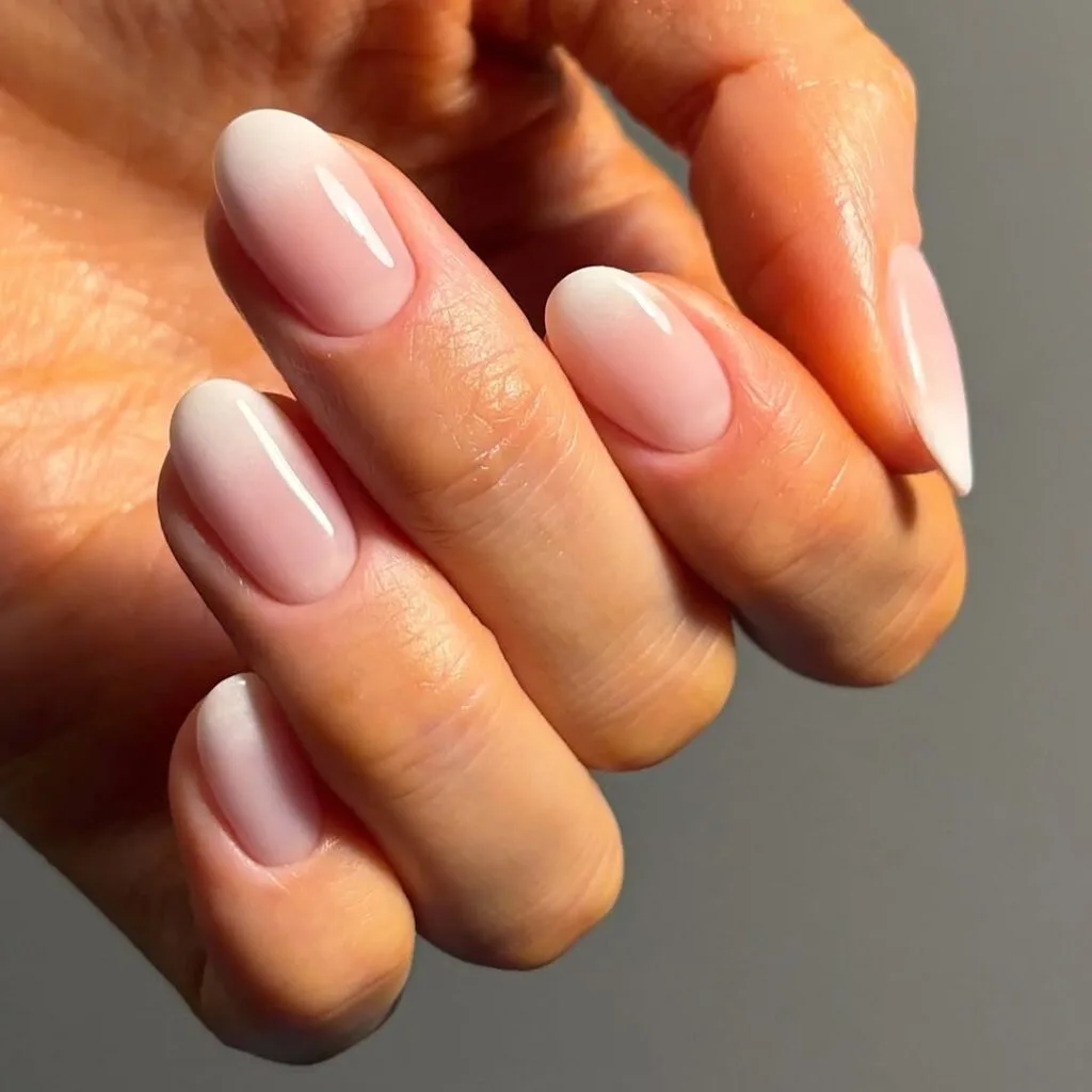 Baby pink neutral almond nails with milky white ombré, glossy, delicate, and feminine.