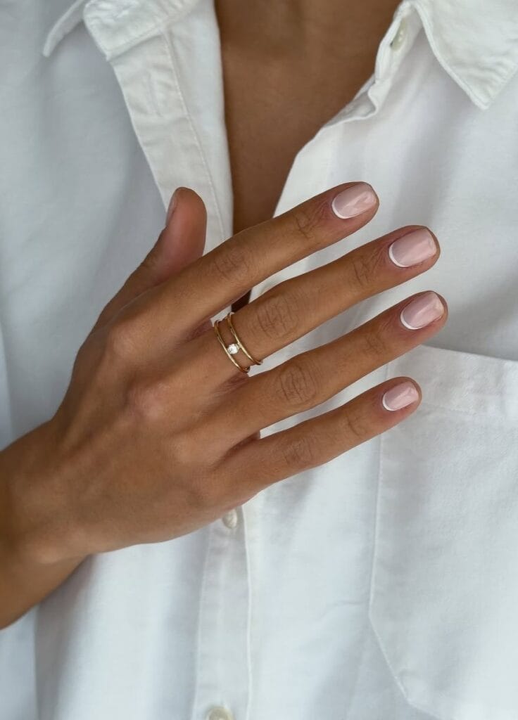 Old money nails with reverse French white base, short and rounded, styled with white shirt and gold ring.

