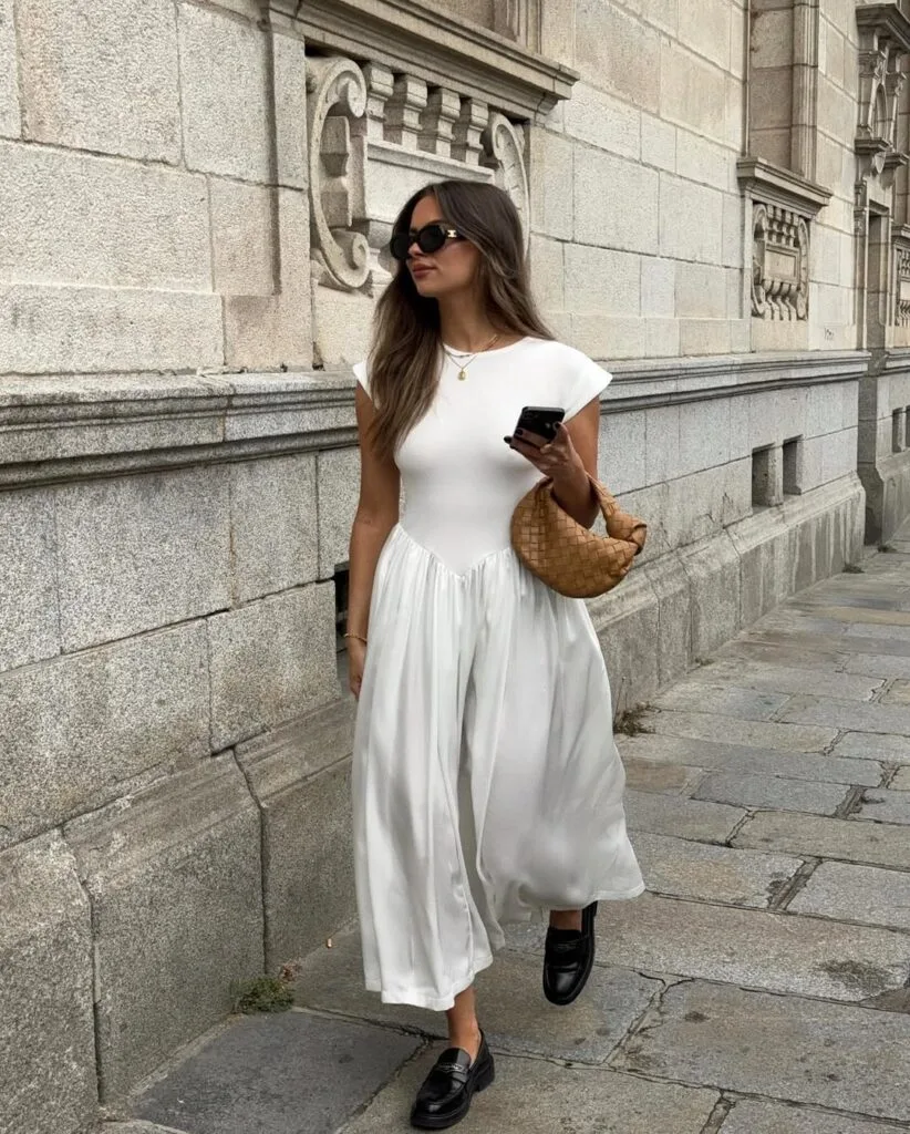 Woman in white maxi dress, black loafers, tan woven bag, sunglasses; city stroll loafers outfit