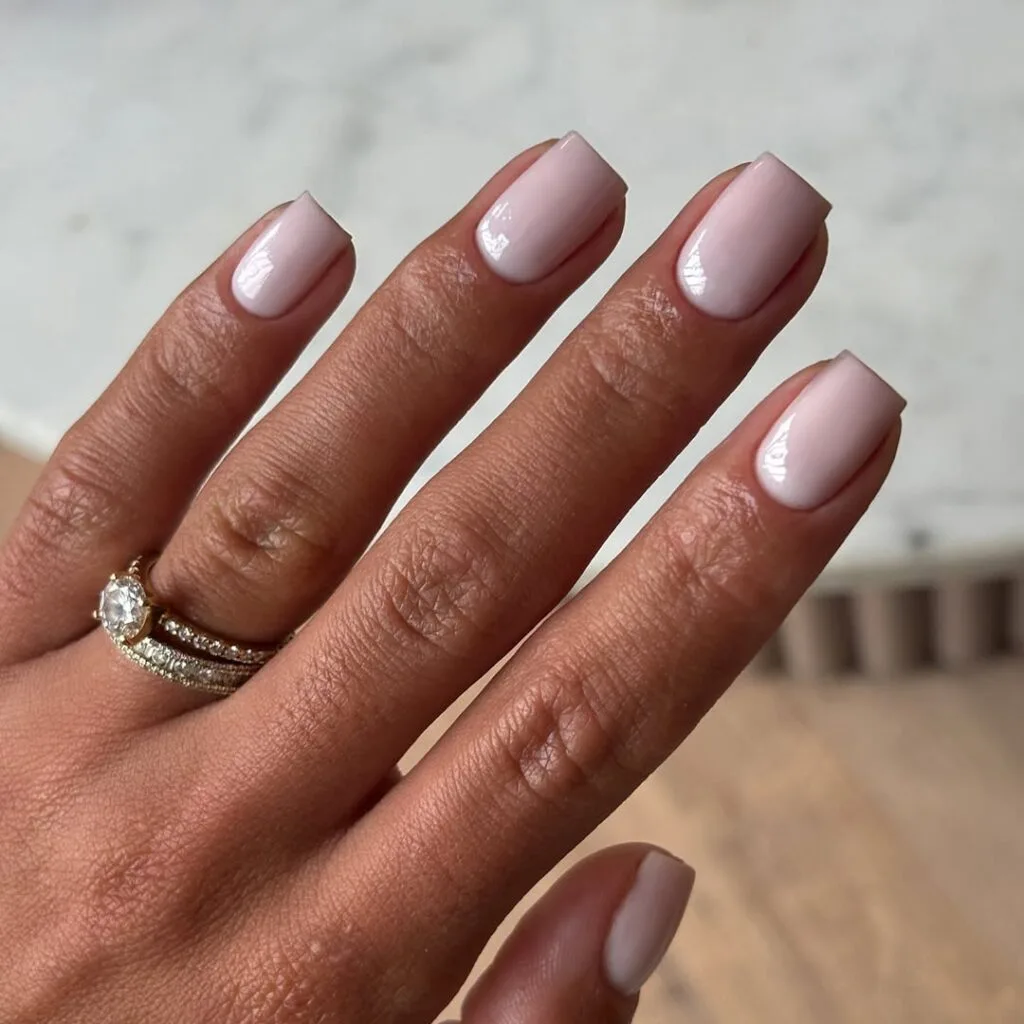 Soft pink nude neutral nails, short square shape, creamy finish, with sparkly engagement ring.