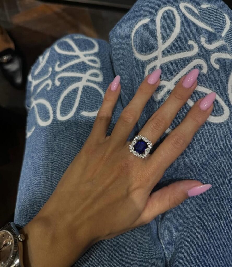 Glossy pointed pink old money nails, worn with statement sapphire ring and embroidered jeans.
