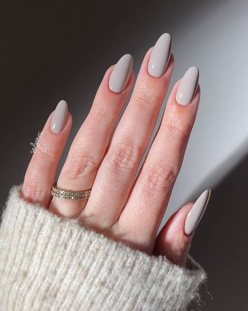 Taupe neutral almond nails, cashmere finish, glossy, styled with cream knit sweater.
