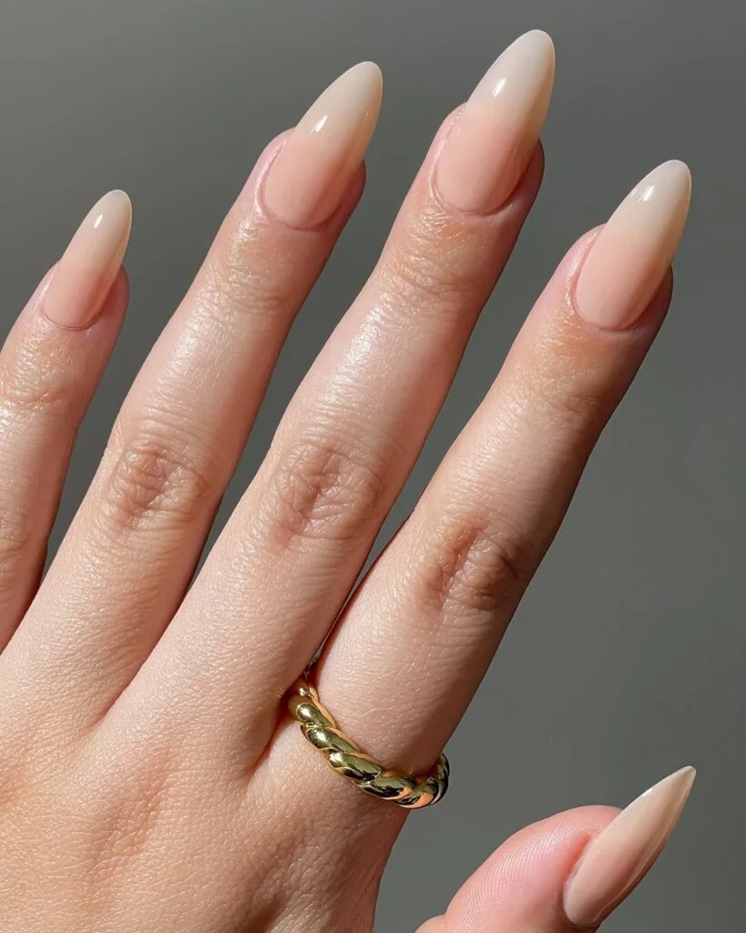Almond shaped neutral nails, latte beige fade, glossy, and elongated minimalist style.