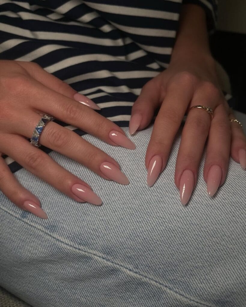 Almond blush nude nails, glossy finish, chic and feminine with denim background.
