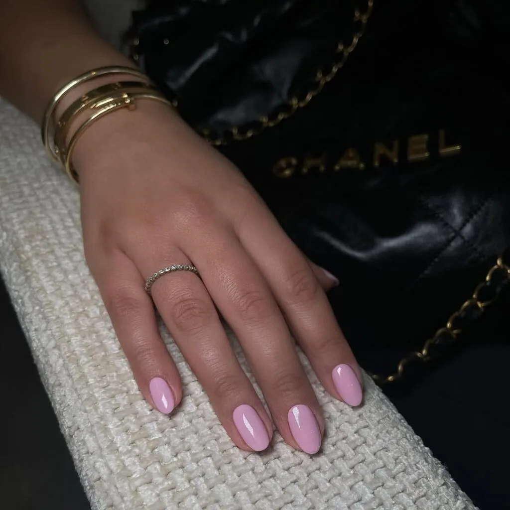Glossy pink old money nails with gold bracelets, styled with a Chanel bag for chic, luxe effect.